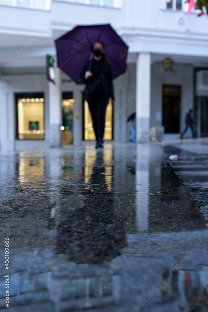 Mujer joven con un paraguas paseando por la ciudad en un dia lluvioso