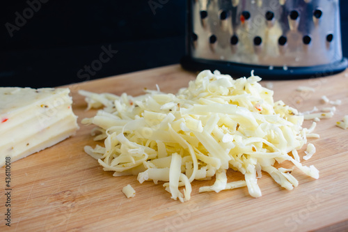 Shredded Pepper Jack Cheese: Shredded cheese and a box grater on a bamboo cutting board photo