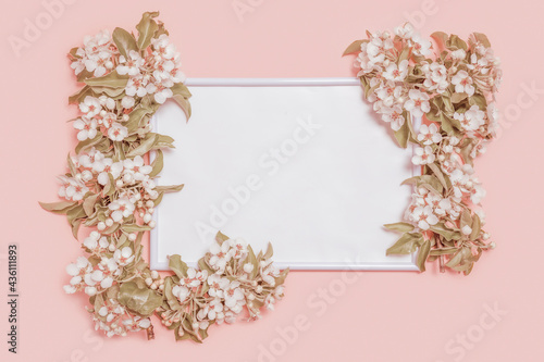 Creative layout with blossoming pear branches and photo frame on pastel pink background. Spring minimal concept. Flat lay, copy space, top view. Toning process .
