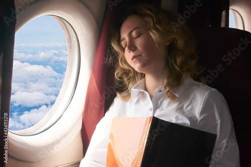Fotografie young woman dozed off in the cabin of a flying plane