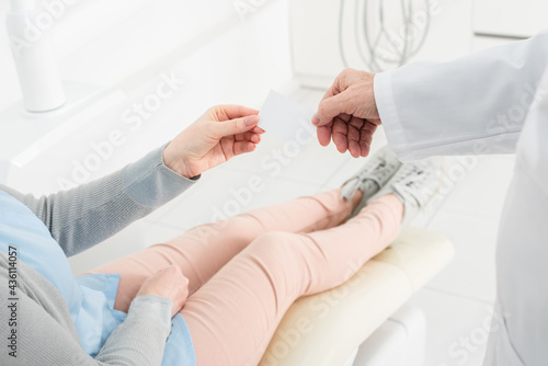 partial view shot of female patient and male dentist hands holding empty card in dental clinic.