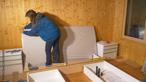 CLOSE UP: Young woman moving into her house unpacks the headboard of her bed.