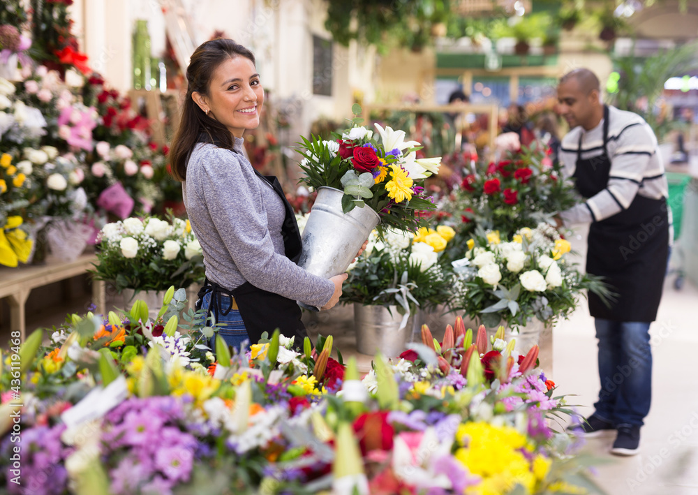 Fototapeta premium Florist in an apron creates bouquets in a flower shop