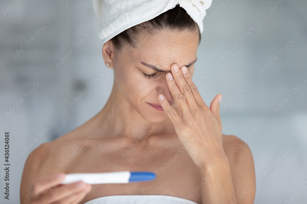 Frustrated heartbroken young woman holding pregnancy tester with unknown result. Upset girl in towels crying in bathroom due to non pregnancy and possible infertility. Fertility problems concept Frustrated heartbroken young woman holding pregnancy tester with unknown result. Upset girl in towels crying in bathroom due to non pregnancy and possible infertility. Fertility problems concept