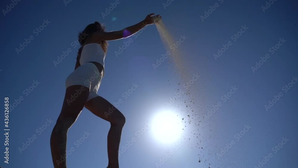 Sand falls through woman's fingers with sky background in slow motion. Time passing concept Sand falls through woman's fingers with sky background in slow motion. Time passing concept