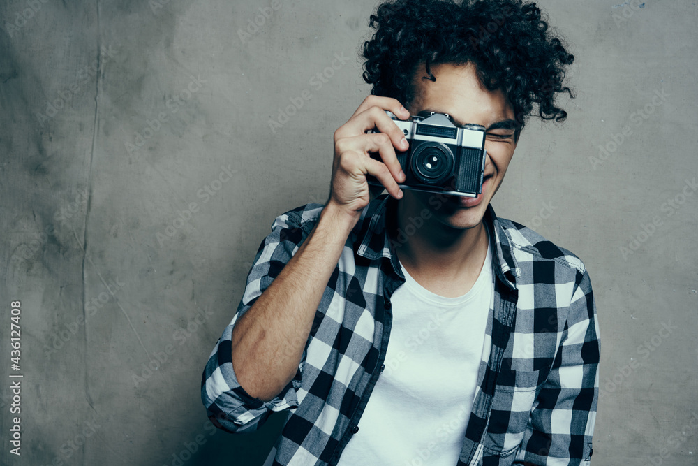 guy with a camera in his hands on a gray background indoors hobby plaid shirt model guy with a camera in his hands on a gray background indoors hobby plaid shirt model