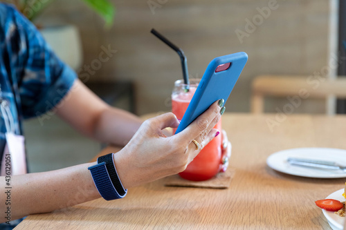 Woman playing mobile phone With watermelon smoothie placed on the side