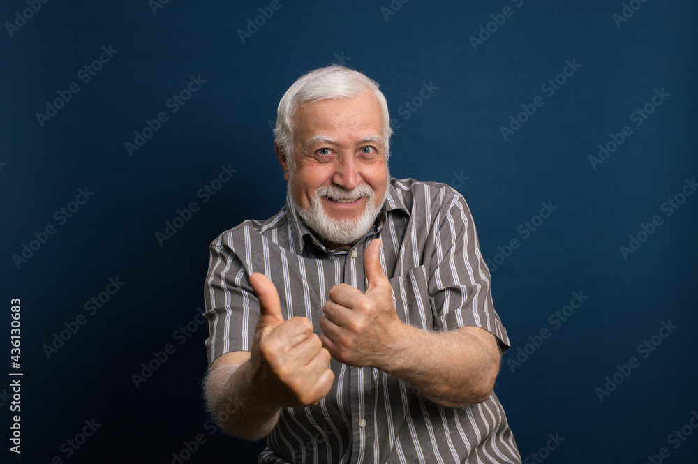 elderly gray-haired man in glasses and black shirt, grandfather, shows likes, emotions in the frame, waist portrait, blue background, studio elderly gray-haired man in glasses and black shirt, grandfather, shows likes, emotions in the frame, waist portrait, blue background, studio