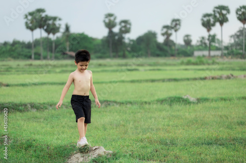 happy little Asian boy run on the field