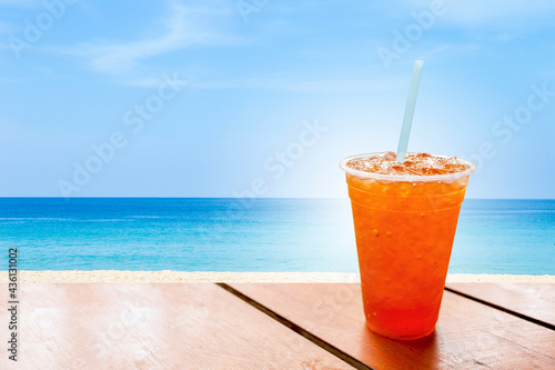 Ice tea in plastic cup over the beach, cold soft drink, summer concept
