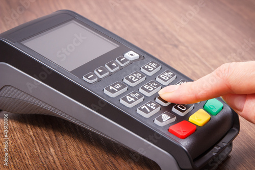 Payment terminal and finger entering PIN code. Credit card reader using for cashless paying