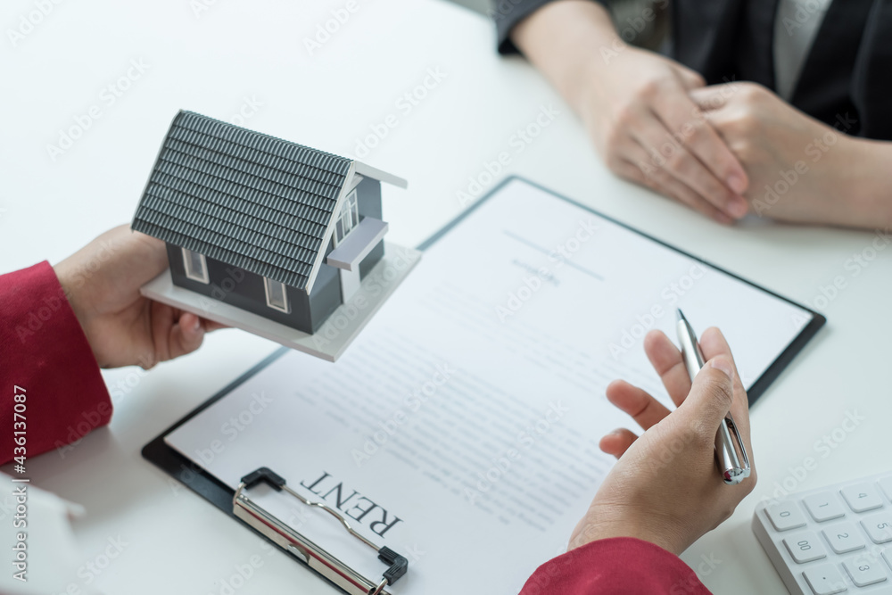 A real estate agent with a House model is talking to clients about buying home insurance. Real estate Home insurance concept A real estate agent with a House model is talking to clients about buying home insurance. Real estate Home insurance concept