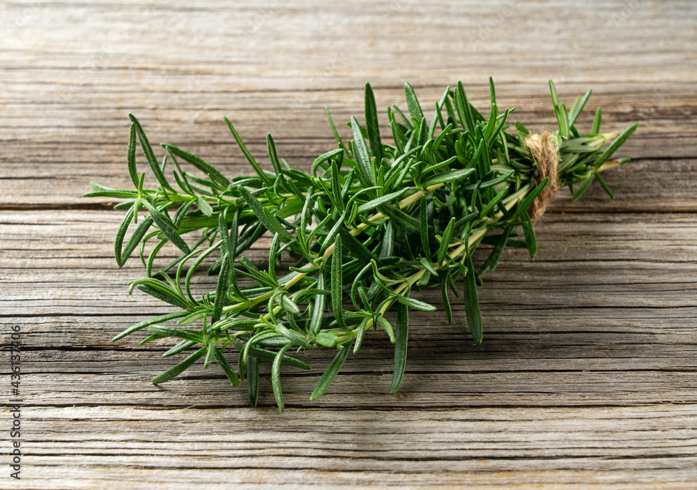 A bunch of rosemary placed against a wooden background. A bunch of rosemary placed against a wooden background.