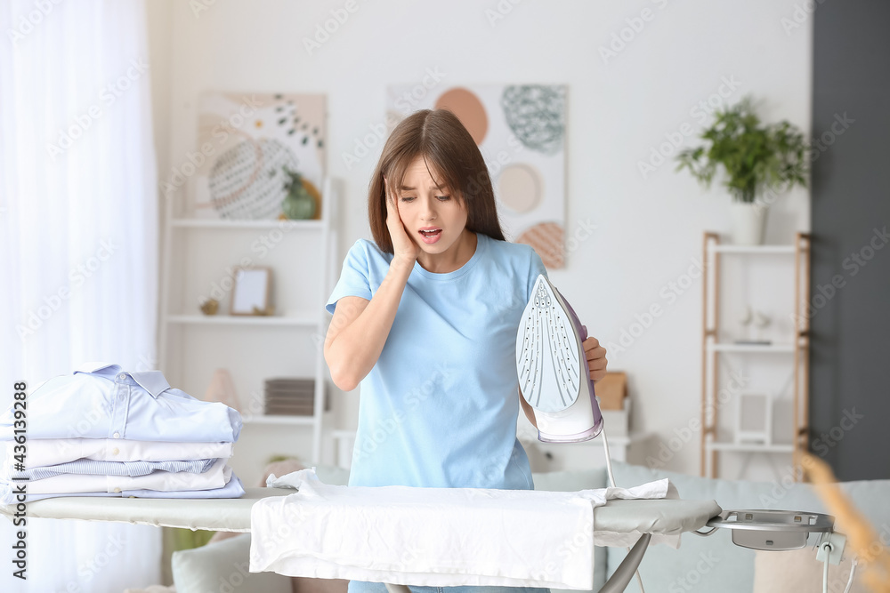 Shocked young woman ironing laundry at home Shocked young woman ironing laundry at home