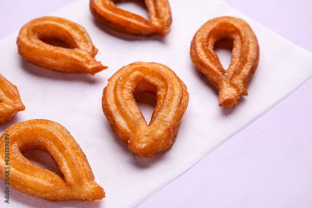 Parchment with tasty churros on color background, closeup Parchment with tasty churros on color background, closeup