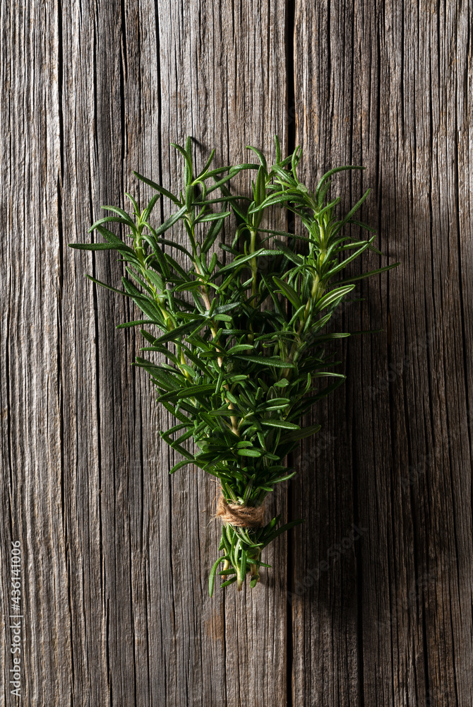 A bunch of rosemary placed against a wooden background. A bunch of rosemary placed against a wooden background.