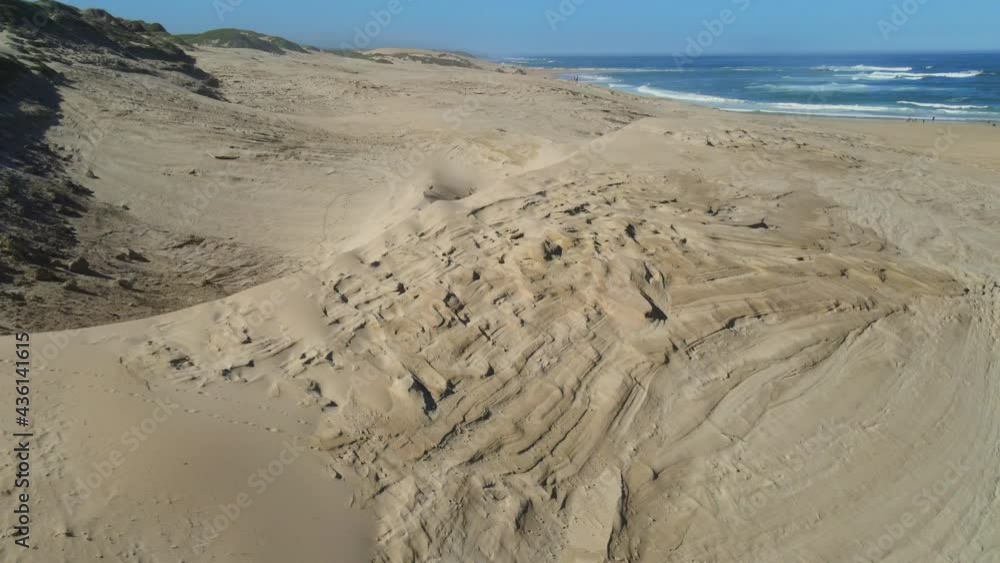 Drone flying away from sand dunes seen at beach Drone flying away from sand dunes seen at beach