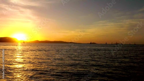 Taken from another boat during a sunset cruise, A number of sail boats can be seen  racing in the evening off Airlie beach North Queensland Auastralia silhouetted against a colorful sunset.backdrop photo