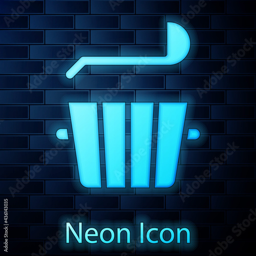 Glowing neon Sauna bucket and ladle icon isolated on brick wall background. Vector