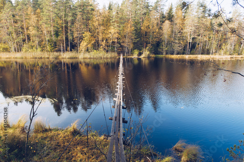 Narrow long wooden suspension bridge over the lake in Karelia, Russia. Beautiful autumn season landscape with river and forest stock photography