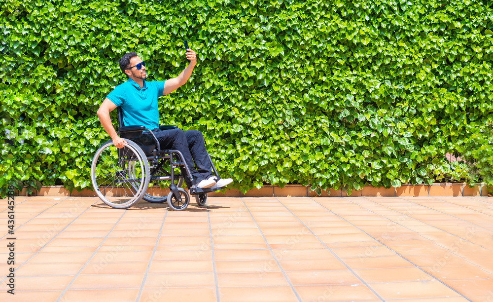 Spanish man in a wheelchair taking a selfie with blue sunglasses and a