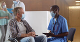 African doctor in safety mask consulting disabled man patient in hospital waiting room
