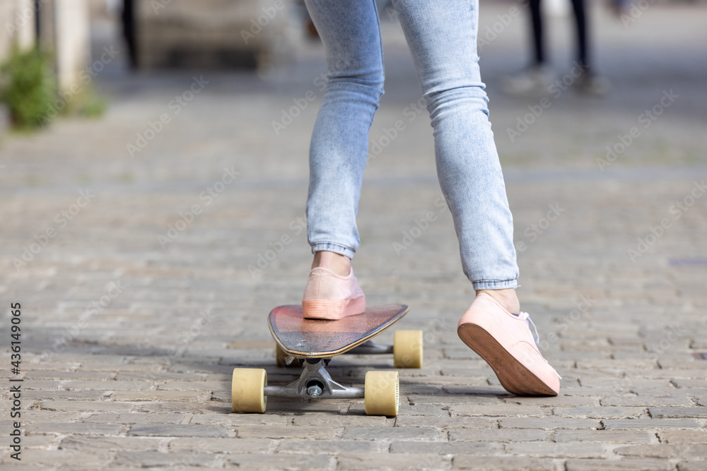 Close-up of female feet of a girl wearing pink sneakers and a jeans on skateboard on the background of the city streets. High quality photo Close-up of female feet of a girl wearing pink sneakers and a jeans on skateboard on the background of the city streets. High quality photo