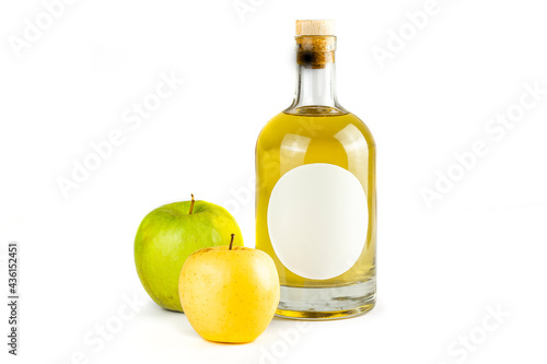 Fresh apples and bottle with fruit brandy. Bottle with oval label, amber liquid and various color apples isolated on white background. Homemade fruit alcohol concept.