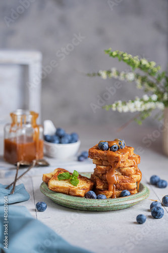 Homemade French toasts with berries  caramel on white table. Beautiful breakfast or dessert. Studio image with copy space  bright rustic background.