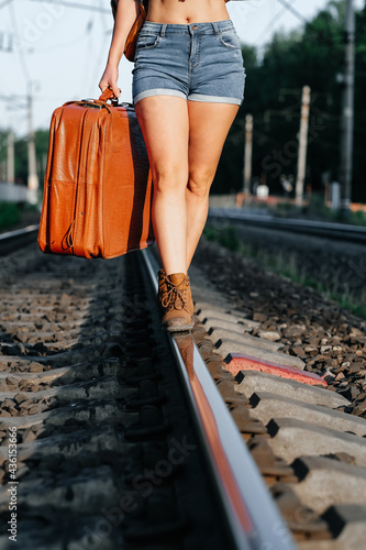 landscape with railway leading lines. A girl with a suitcase and a backpack. The traveler.