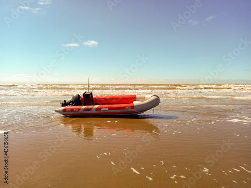 Rigid hull inflatable boat with outboard motor in the shore beaten by the waves. Used to fish at sea photo