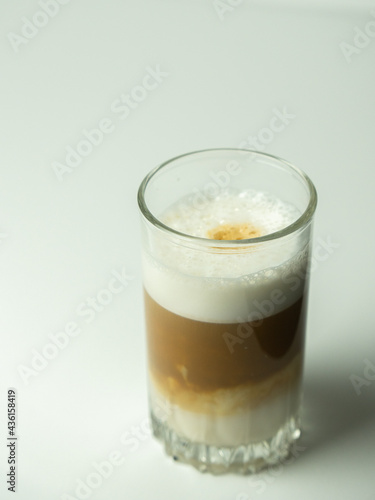 Glass of latte coffee on light background