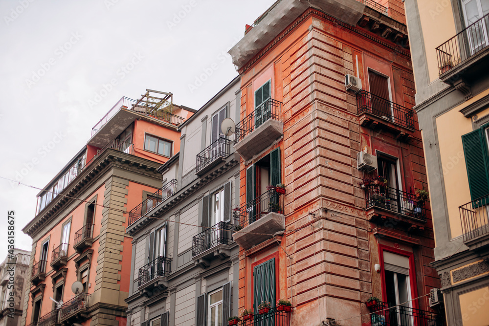 facades of houses of an old European city. Italian shutters on the windows are green. French balconies on the facade of the old building. European architecture
