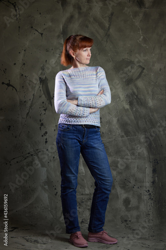 Portrait of a Caucasian woman in full growth in jeans in a studio on gray background. High resolution photos