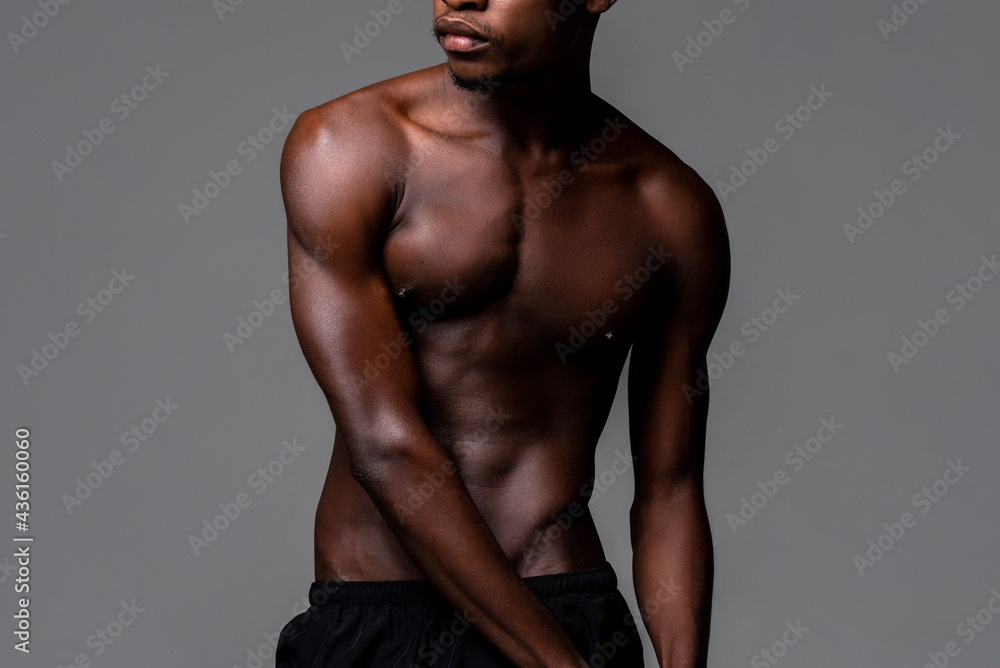 Shirtless lean young African man body in studio isolated gray background