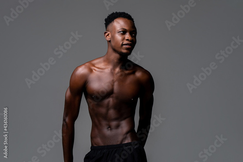 Shirtless young lean fit African man in isolated light gray background