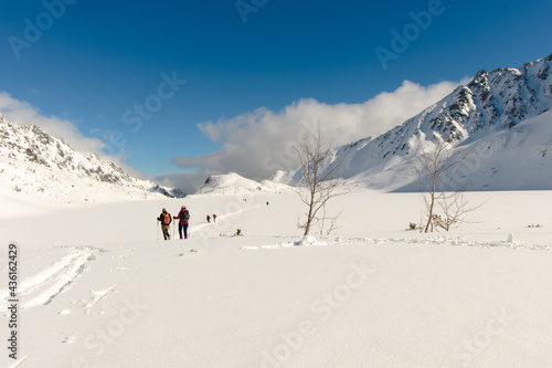 Tourists on the frozen large pond in the valley of the Five Ponds. Winter Tatra Mountains, mountain landscape. January in the Valley of Five Ponds in the Tatra Mountains.