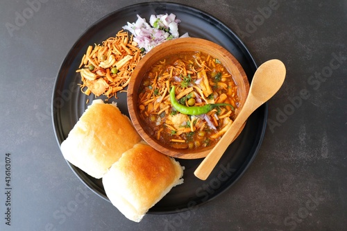 Spicy Misal Pav or usal Pav is a traditional snack or Chaat food from Maharashtra, India. Served with chopped onion, lemon wedges and farsan. Selective focus with copy space photo
