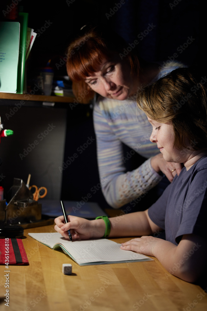 Fototapeta premium Photo of a boy doing homework at the table with mom. High resolution photos
