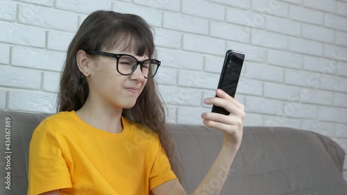 Girl feel tired eyes. A young girl in glasses hold her telephone and try to read something.