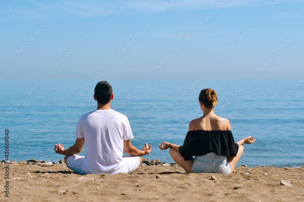 A couple is engaged in yoga on the beach against the background of the sea. Health and sports. A woman and a man on the shore of the ocean are meditating and relaxing. Summer and travel. A couple is engaged in yoga on the beach against the background of the sea. Health and sports. A woman and a man on the shore of the ocean are meditating and relaxing. Summer and travel.