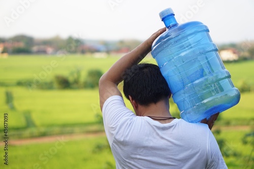 Man carrying a bottle of drinking water on his shoulder to service the villagers in rural of Thailand that lack of drinking water in summer. Concept healthy strong man. Service delivery man. photo