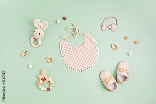 Photos Baby shoes, bib and teether on pastel background