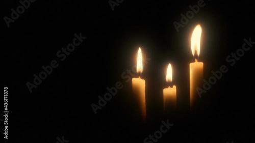 Three burning candles against a black background with copy space.