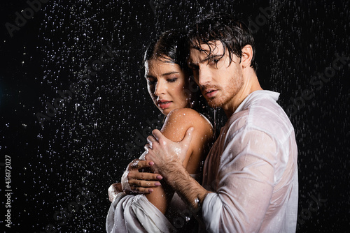 wet sexy romantic couple passionately hugging on black background with side lighting on black background