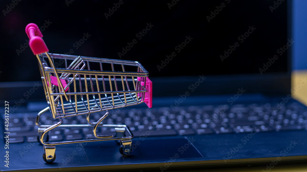 Online shopping. A laptop and mini shopping cart and gadgets