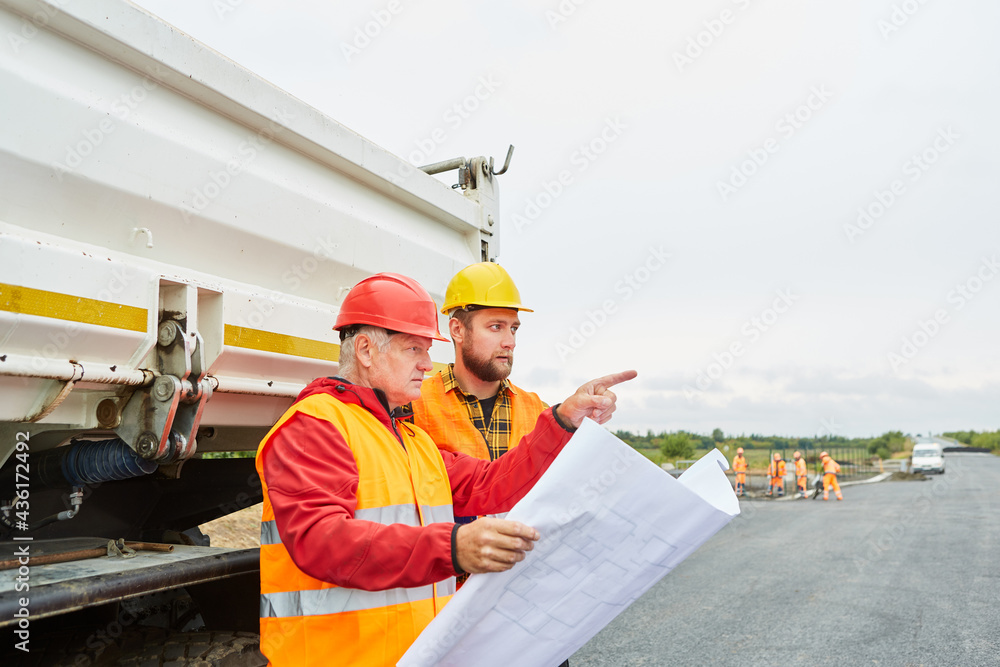 Bauarbeiter mit Grundriss auf der Baustelle im Hausbau Bauarbeiter mit Grundriss auf der Baustelle im Hausbau