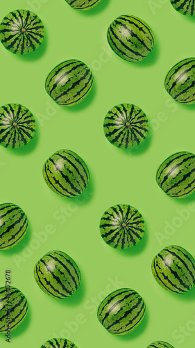 Geometrical pattern of fresh watermelons isolated on a bright green background. Creative food concept. Minimal summer fruit idea. Flat lay, top view.