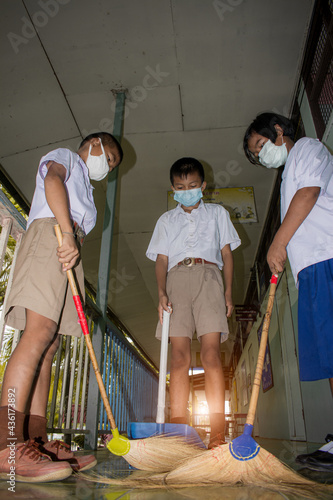 Surin, THAILAND - October 12, 2020:Three Thai young students in school uniforms are sweeping and cleaning the corridor of the School building floor. in their school every morning. They are aware of Co