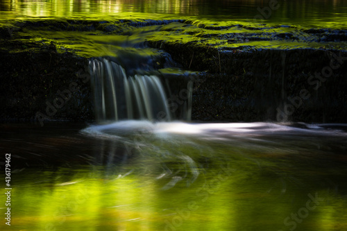 Cascading waterfall cascades in Estonia in green light at summertime